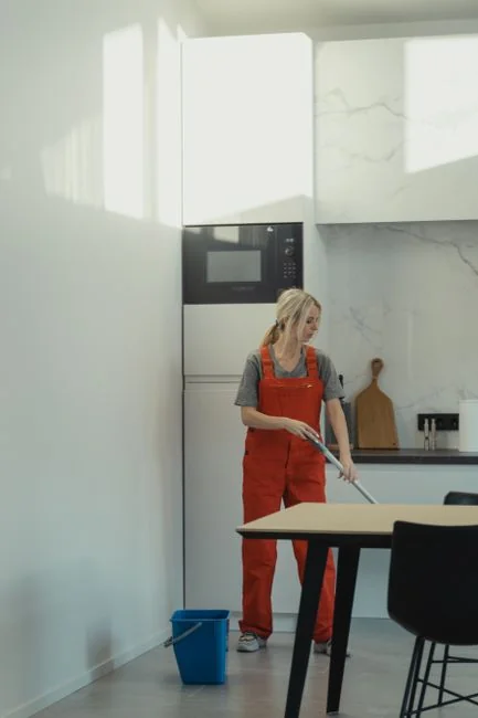 Cleaning crew in red uniforms with equipment approaching a modern house exterior.